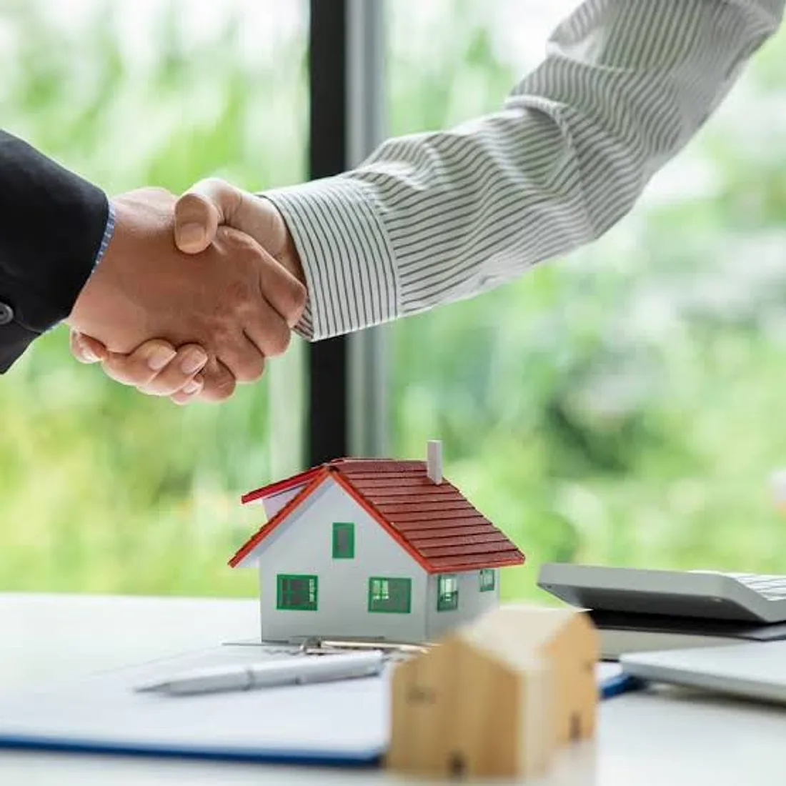 A property owner and manager shaking hands over a model home